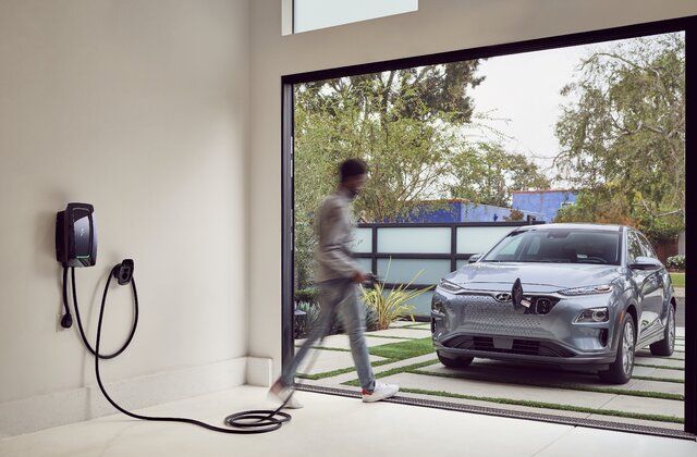 En person går forbi en Zaptec ladestander mod en elektrisk Hyundai i en indkørsel.